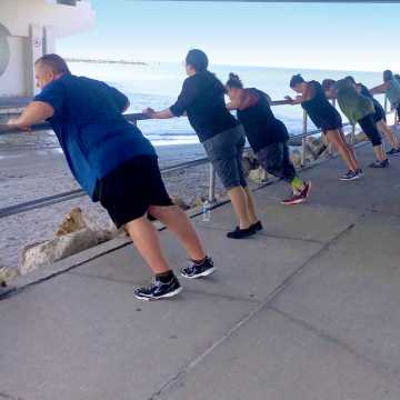 A group of weight loss campers stretching at the waters edge at Johns Pass